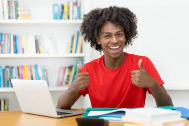 Başarılı afro-amerikan erkek öğrenci evde masa başında öğreniyor.