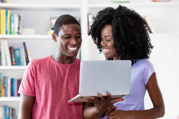 Video conference of laughing african american couple in quarantine indoors at home