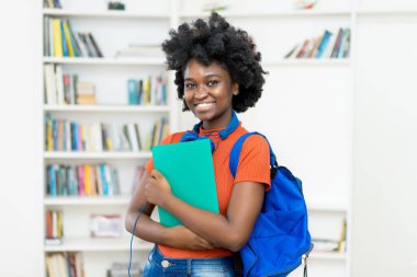 Sırt çantası ve evrak işleriyle dolu güzel Afro-Amerikan üniversite öğrencisi.