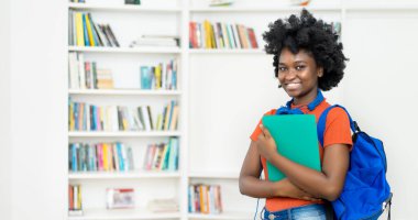 Sırt çantası, evrak işleri ve sınıfta fotokopi alanı olan Afro Amerikalı genç bir üniversite öğrencisi.