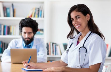 Hastanede doktorla birlikte gülen Hintli tıp öğrencisi.