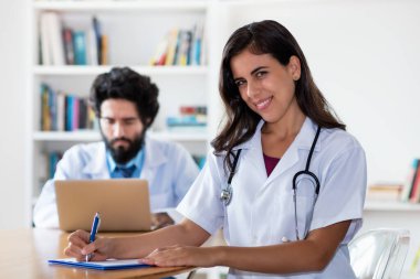 Hastanede doktorla birlikte gülen Latin bir tıp öğrencisi.