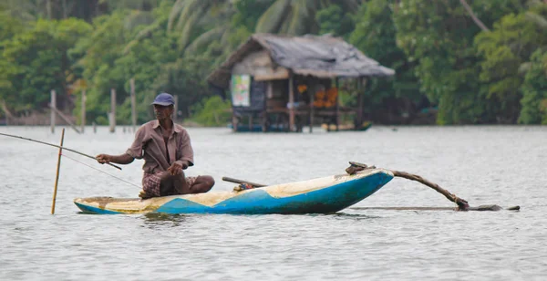 Sri Lankan Fluss, srilankischer Tourismus, Fischer vom See in Aktion beim Angeln in der Dämmerung, srilankische Kultur und Tourismus. Holzboot mit Angelrute. — Stockfoto