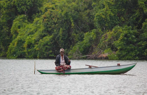 Sri Lankaanse rivier, Srilankaanse toerisme, Visser van het meer in actie bij het vissen in de schemering, Srilankaanse cultuur en toerisme.houten boot met hengel. — Stockfoto