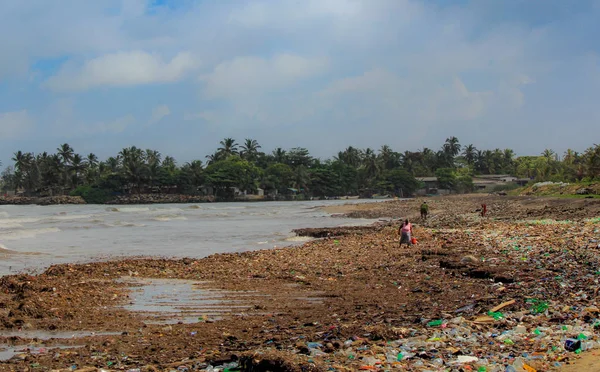 Meeresverschmutzung: Müll, der im sri-lankischen Meer in der Nähe von Kolumbien abgeladen wurde. Frauen sammeln Plastikgegenstände in einem Müllhaufen, den die Brandung aus dem Meer geholt hat — Stockfoto