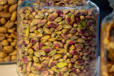 Beyaz arka planda beyaz ahşap masa üzerinde cam kavanozlarda çeşitli fındık ve tohumlar. Vejetaryen ve organik gıda kavramı. Fotoğraf seti.