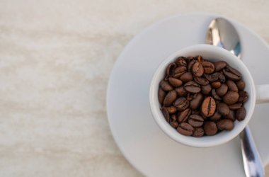 Beyaz arka planda kahve fincanı ve fasulye. Metnin için kopyalama alanı olan üst görünüm