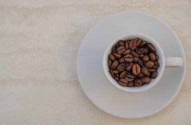 Beyaz arka planda kahve fincanı ve fasulye. Metnin için kopyalama alanı olan üst görünüm