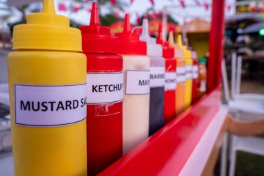 Bir yemek festivalinde yemek kartında kullanılmaya hazır bir sürü sos şişesi var.