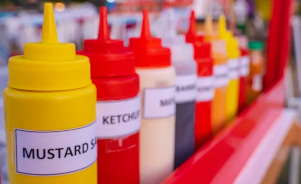 Multiple flavor sauce bottles in a food card at a food festival ready to be used
