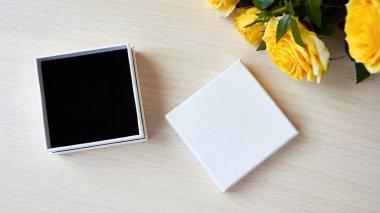 Sunum için üst görünüm. Mücevher için boş kutu, hediye. Logo yeri, satış metni. Masada sarı güller var..