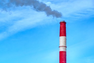 Mavi gökyüzünün arka planında dumanı olan kırmızı-beyaz baca. Çevre kirliliği, kötü ekoloji, endüstri, doğayı koruma, küresel ısınma, CO2