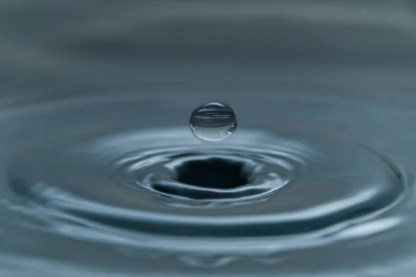 Una goccia d'acqua che si libra nell'aria prima di colpire una superficie dell'acqua, che causerà una bella spruzzata, foto ravvicinata — Foto Stock
