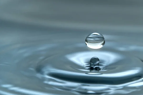 Uma gota de água pairando no ar antes de atingir uma superfície de água, o que causará um belo respingo, foto de close-up — Fotografia de Stock