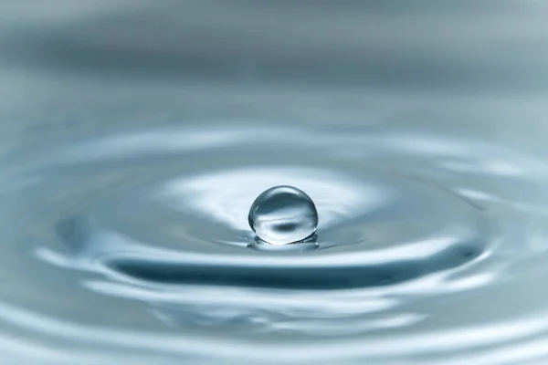 Una goccia d'acqua che si libra nell'aria prima di colpire una superficie dell'acqua, che causerà una bella spruzzata, foto ravvicinata — Foto Stock