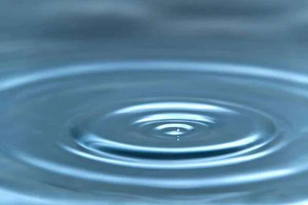 Uma gota de água pairando no ar antes de atingir uma superfície de água, o que causará um belo respingo, foto de close-up — Fotografia de Stock