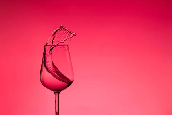Mooie spatten water in een wijnglas, met rode filter, close-up met kopieerruimte. — Stockfoto