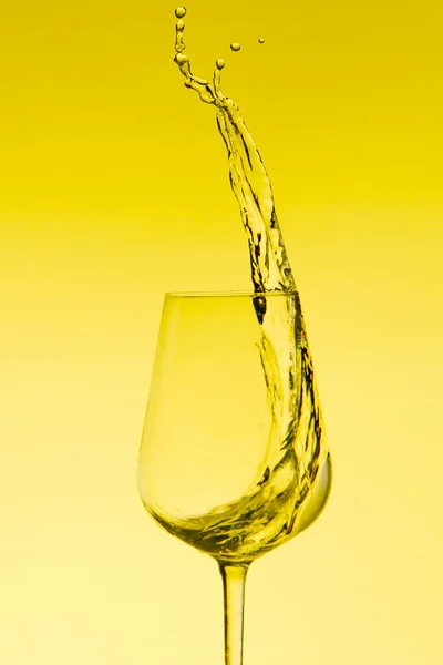 Krásné cákance vody ve sklenici vína, se žlutým filtrem, zblízka s kopírovacím prostorem. — Stock fotografie