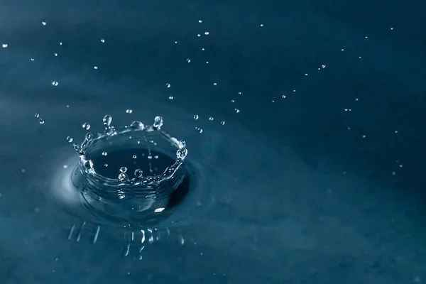 Vacker stänk av vatten droppe på vattenytan, makrofoto — Stockfoto