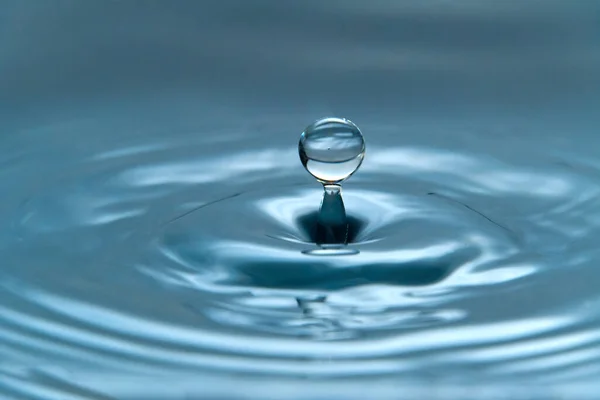 Uma gota de água pairando no ar antes de atingir uma superfície de água, o que causará um belo respingo, foto de close-up — Fotografia de Stock