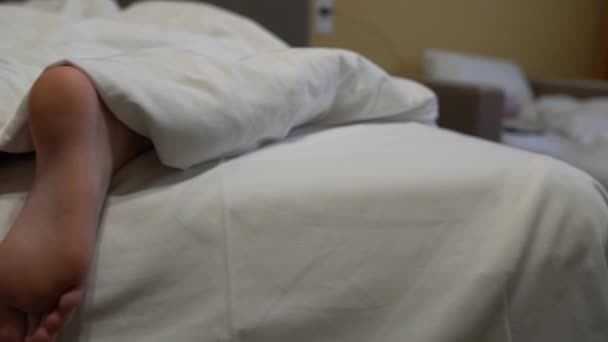 Три пары ног в постели под белым одеялом — стоковое видео