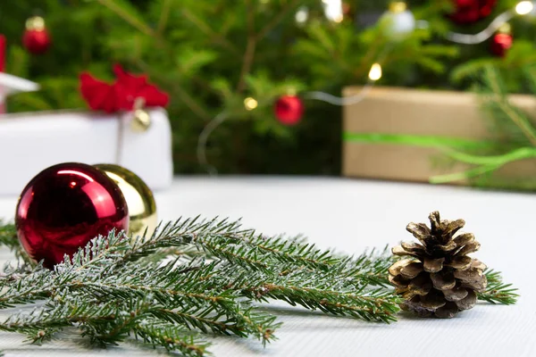 Bela composição de Natal. Caixas de presente e árvore de Natal com luzes no fundo. Decoração bola vermelha com ramo de abeto. Cenário de Natal para o seu cartão de saudação com espaço para texto . — Fotografia de Stock