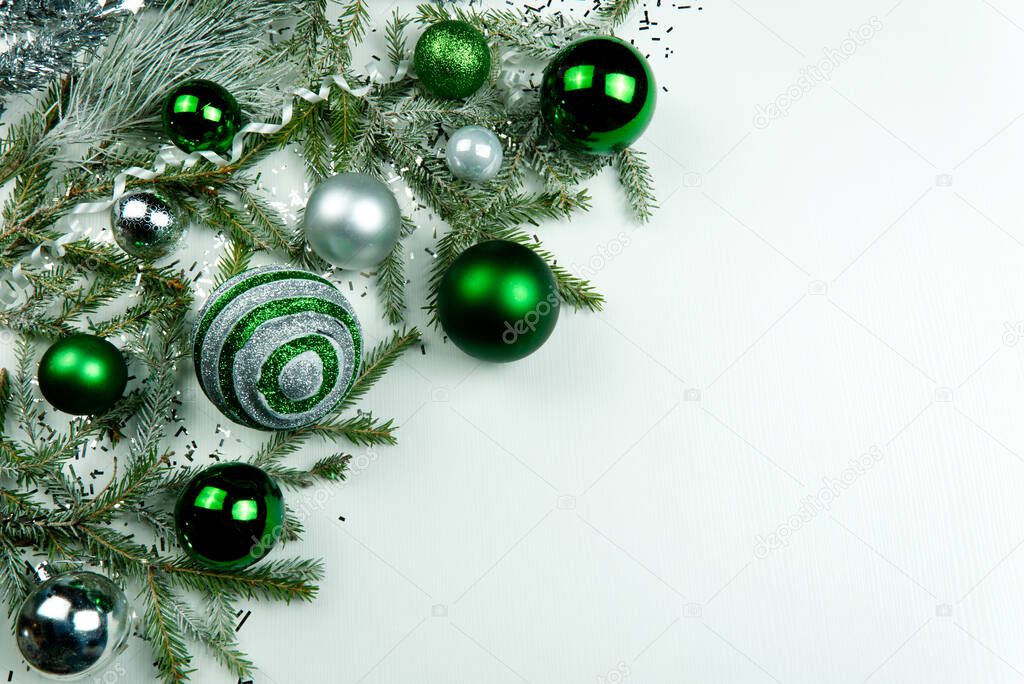 Modern Christmas composition. Christmas balls, green and silver decorations on white background. Flat lay, top view, copy space. close up photo. can be used us postcard or Christmas banner