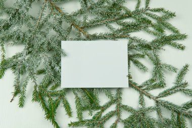 Beyaz kart, köknar dallarının arka planında koni ve beyaz ahşap arka planda Noel oyuncakları var. Model yap, boşluğu kopyala