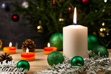 Mum yakmak ve Noel süslemeleri. Noel ağacı için yeşil toplar ve ahşap zemindeki köknar dalı için bokeh arka planlı. Boşluğu kopyala