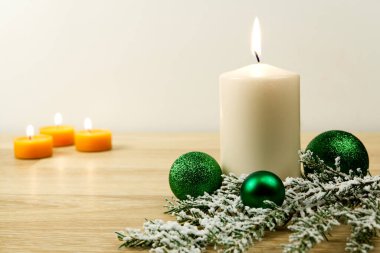 Mum yakmak ve Noel süslemeleri. Noel ağacı için yeşil toplar ve ahşap zemindeki köknar dalı için bokeh arka planlı. Boşluğu kopyala