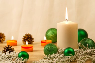 Mum yakmak ve Noel süslemeleri. Noel ağacı için yeşil toplar ve ahşap zemindeki köknar dalı için bokeh arka planlı. Boşluğu kopyala