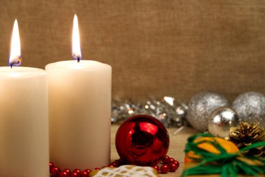 Mum yakmak ve Noel süslemeleri. Noel ağacı için yeşil toplar ve ahşap zemindeki köknar dalı için bokeh arka planlı. Boşluğu kopyala