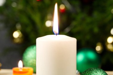 Mum yakmak ve Noel süslemeleri. Noel ağacı için yeşil toplar ve ahşap zemindeki köknar dalı için bokeh arka planlı. Boşluğu kopyala
