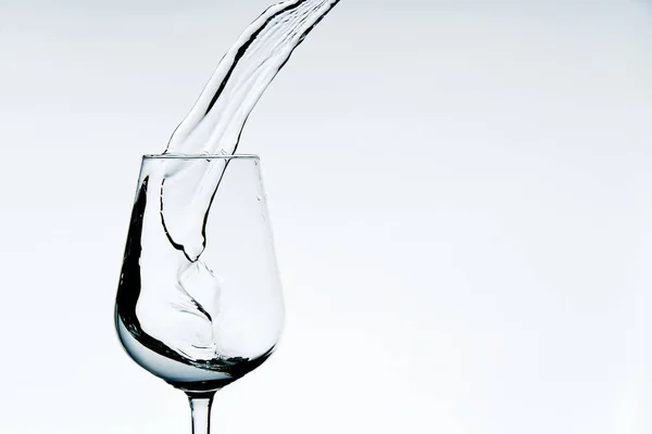 Schöne Spritzer Wasser in einem Weinglas, isoliert auf weiß, Nahaufnahme mit Kopierraum. — Stockfoto
