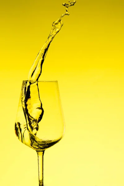 Krásné cákance vody ve sklenici vína, se žlutým filtrem, zblízka s kopírovacím prostorem. — Stock fotografie