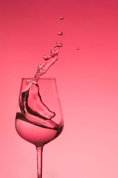 Hermosas salpicaduras de agua en una copa de vino, con filtro rojo, cerca con espacio de copia . — Foto de Stock