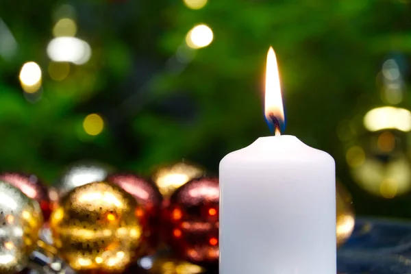 Brennende Kerzen und Weihnachtsdekoration. grüne Kugeln für Weihnachtsbaum und Tannenzweig auf Holzboden mit Bokeh-Hintergrund. Kopierraum — Stockfoto