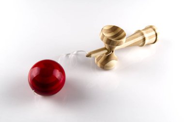 Kendama Japon tahta oyuncağı beyazın üstünde izole edilmiş. Kırmızı bal ile ahşap oyuncak.