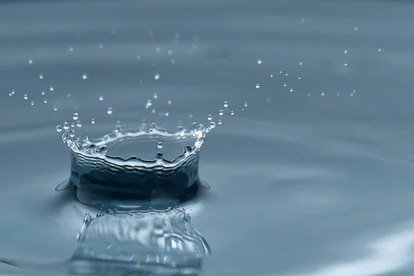 Bella spruzzata di goccia d'acqua sulla superficie dell'acqua, macro foto — Foto Stock