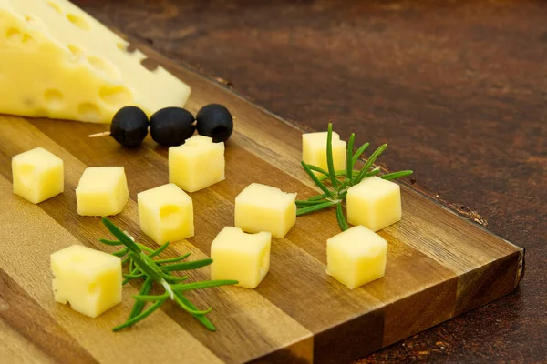 Tranches de fromage aux olives et romarin sur une planche de bois. entrée au fromage de vin — Photo