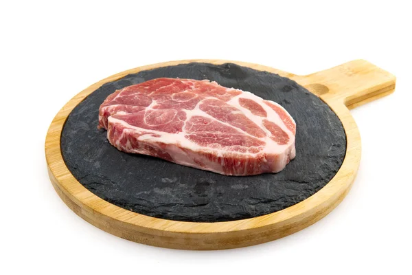 Bife de porco cru em pedra preta e madeira. Porco com temperos: alecrim e pimentão. Bifes de porco crus close-up . — Fotografia de Stock