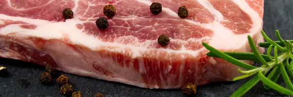 Raw pork steak on black stone and wood. Pork with spices: rosemary and pepper. Close-up raw pork steaks. — Stock Photo, Image