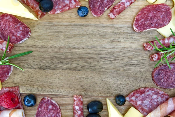 Marco de carne y queso. Snack antipasti con jamón Prosciutto, parmesano, queso azul, melón cantalupo y aceitunas sobre tabla de servir de madera de olivo sobre fondo de piedra oscura — Foto de Stock