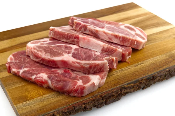 Bife de porco cru na placa de corte de madeira. Porco com temperos: alecrim e pimentão. Bifes de porco crus close-up . — Fotografia de Stock