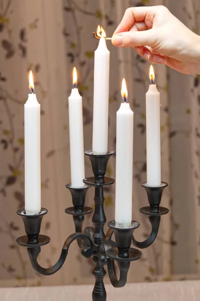 Сжигание свечей в ретро-подсвечнике стоит на столе в комнате. женщина зажигает свечи. Романтическая атмосфера. Чёрный подсвечник. Красивое украшение. Старый или античный стиль . — стоковое фото
