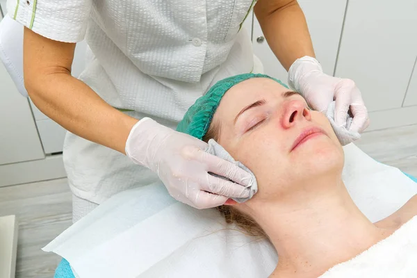 Schoonheidsspecialiste reinigt gezicht. Jonge vrouw in een schoonheidssalon. Cosmetologisch concept. De cosmetoloog voert een procedure uit om het gezicht te reinigen met een probleemhuid. Anti-leeftijd en rimpel. — Stockfoto