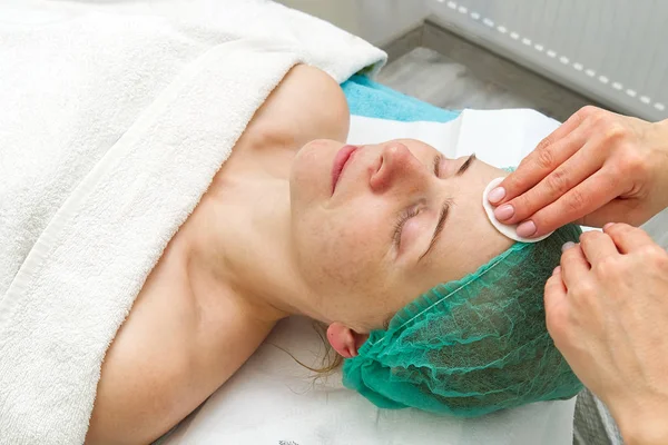 Schoonheidsspecialiste reinigt gezicht. Jonge vrouw in een schoonheidssalon. Cosmetologisch concept. De cosmetoloog voert een procedure uit om het gezicht te reinigen met een probleemhuid. Anti-leeftijd en rimpel. — Stockfoto