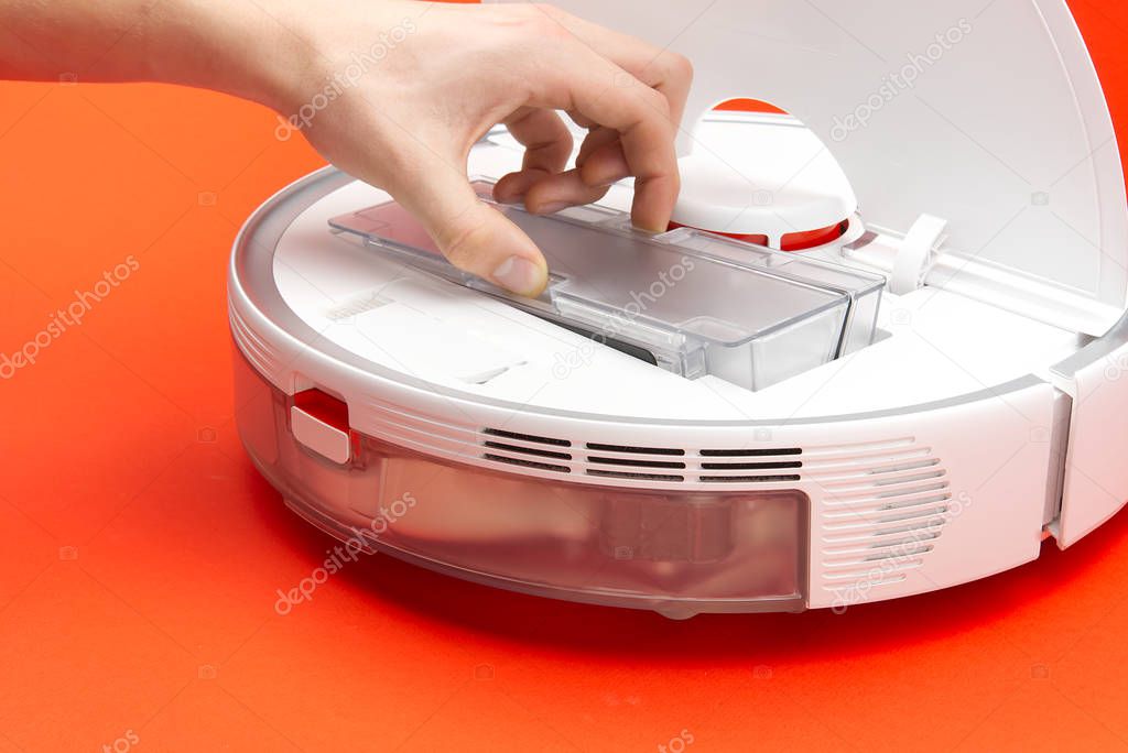 Robot vacuum cleaner, cleaning the trash bin and cleaning the filter. Robot vacuum cleaner isolated on red background.