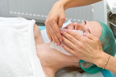 Güzellik uzmanı yüzünü temizler. Güzellik salonunda genç bir kadın. Kozmetoloji konsepti. Kozmetik uzmanı, yüzü sorunlu ciltlerle temizlemek için bir prosedür uyguluyor. Yaş ve kırışıklık önleyici.