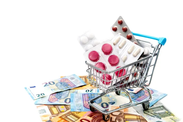 Isolated shopping cart full of medicine with pills and capsules and euro banknotes. money . drug cost concept — 스톡 사진